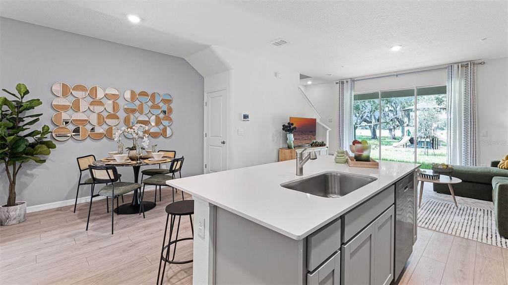 A kitchen island with a sink overlooks an open-concept dining area and living room — 3516 CHROMA STREET, ORLANDO, FL