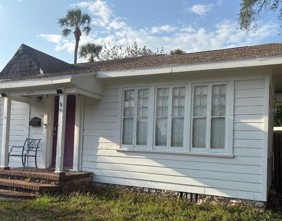A white house exterior features a front porch, a purple door, and large multi-pane windows — 2601 W CLEVELAND STREET, TAMPA, FL