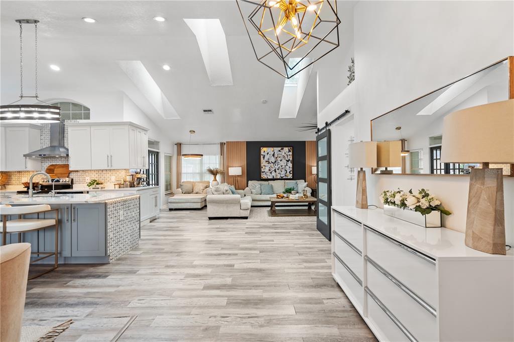 An open-concept living room and kitchen featuring vaulted ceilings, skylights, and light wood flooring — 335 DEBARY AVENUE, DEBARY, FL