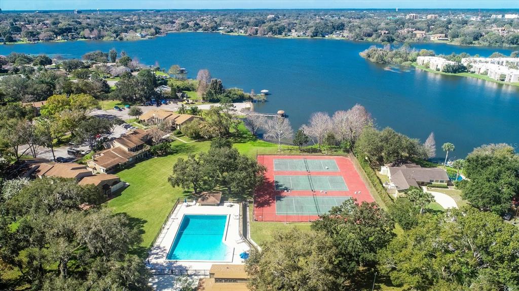 An aerial view shows a swimming pool and tennis courts next to a lake — 626 RED OAK CIRCLE UNIT 106, ALTAMONTE SPRINGS, FL