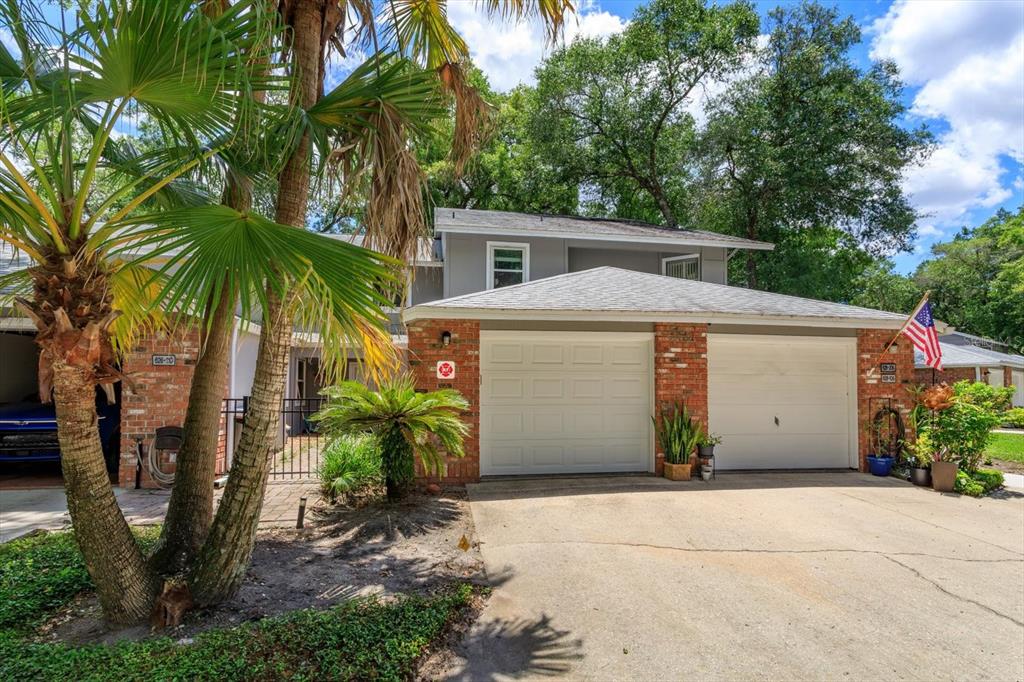 A two-story townhouse with a brick facade, two garage doors, and a palm tree — 626 RED OAK CIRCLE UNIT 106, ALTAMONTE SPRINGS, FL