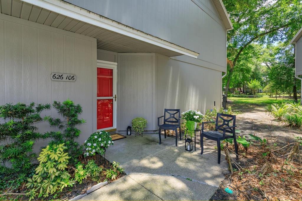 A concrete patio leads to a red front door on a gray-sided building — 626 RED OAK CIRCLE UNIT 106, ALTAMONTE SPRINGS, FL