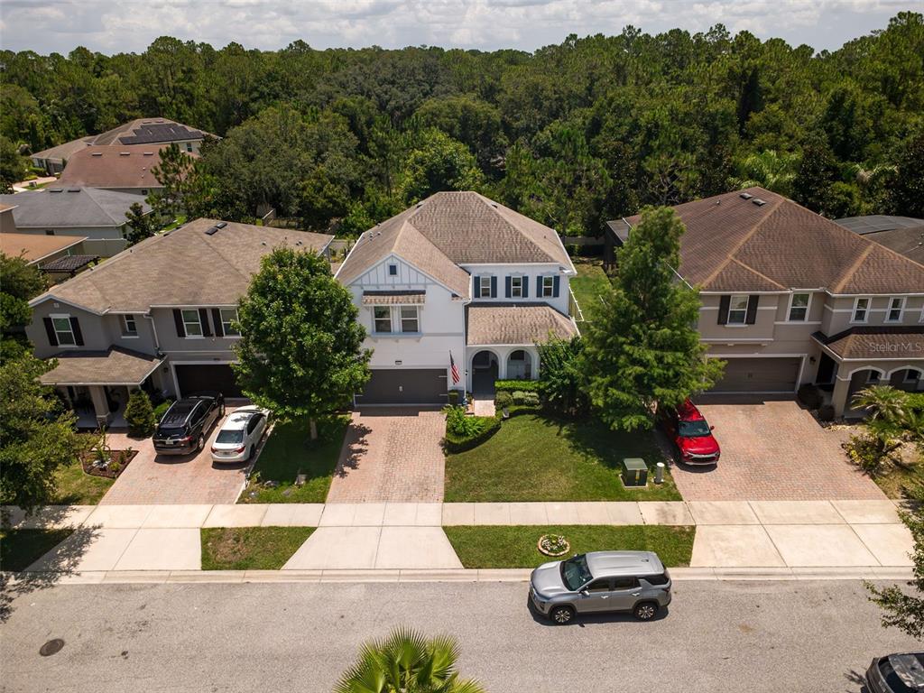 An aerial view shows three suburban houses with driveways and lawns along a paved street — 2317 AVELLINO AVENUE, ST CLOUD, FL