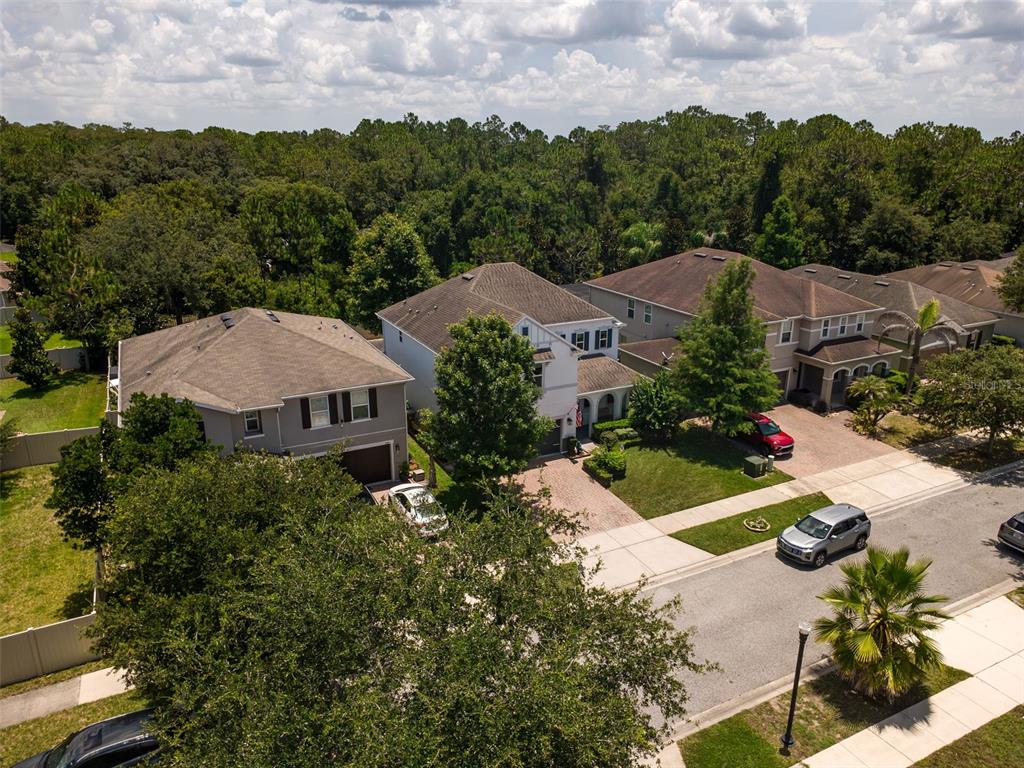 An aerial view of three suburban houses with driveways and surrounding trees under a cloudy sky — 2317 AVELLINO AVENUE, ST CLOUD, FL