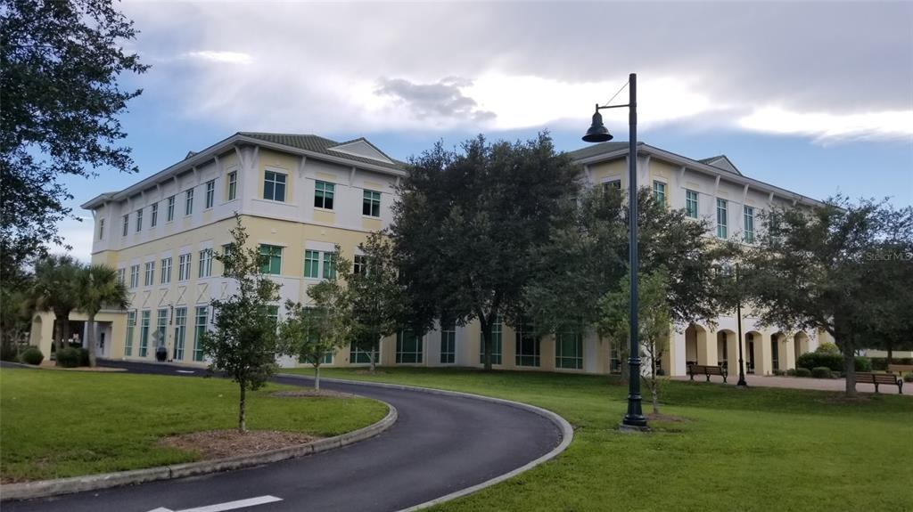 A three-story yellow office building with a curved driveway and surrounding green lawn — 1151219204 DEVONIA CIRCLE, NORTH PORT, FL