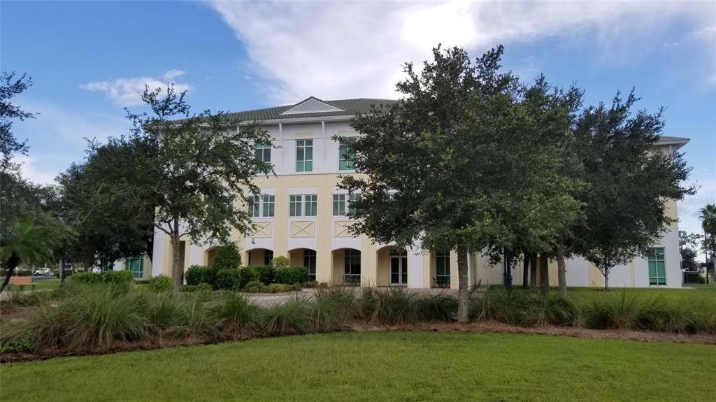 A three-story commercial building with a light yellow facade and arched ground-level entrances — 1151219204 DEVONIA CIRCLE, NORTH PORT, FL