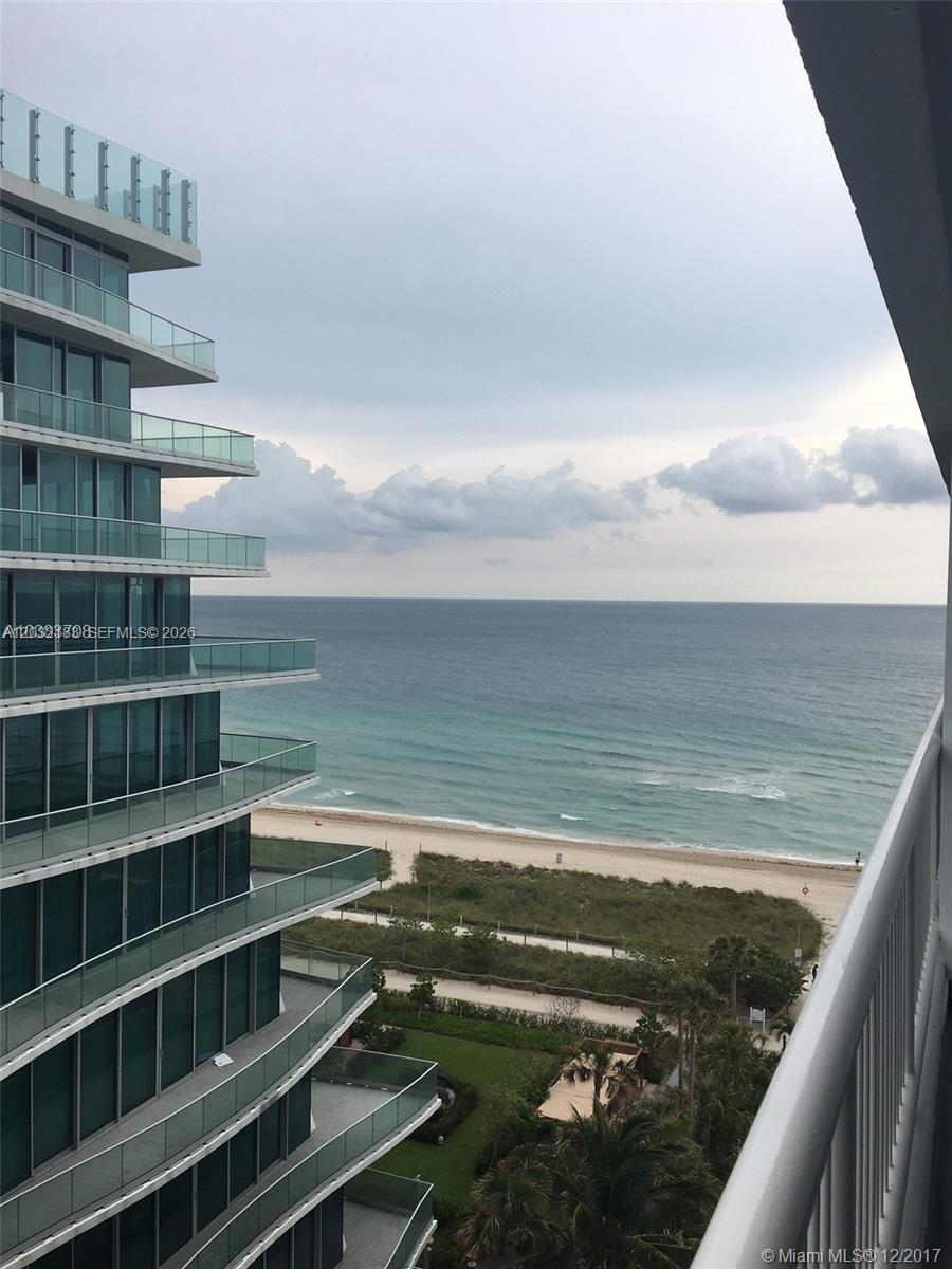 A high-rise balcony view overlooks a sandy beach, ocean, and a neighboring glass building — 9341 Collins Ave # 1006, Surfside FL 33154, SURFSIDE, FL