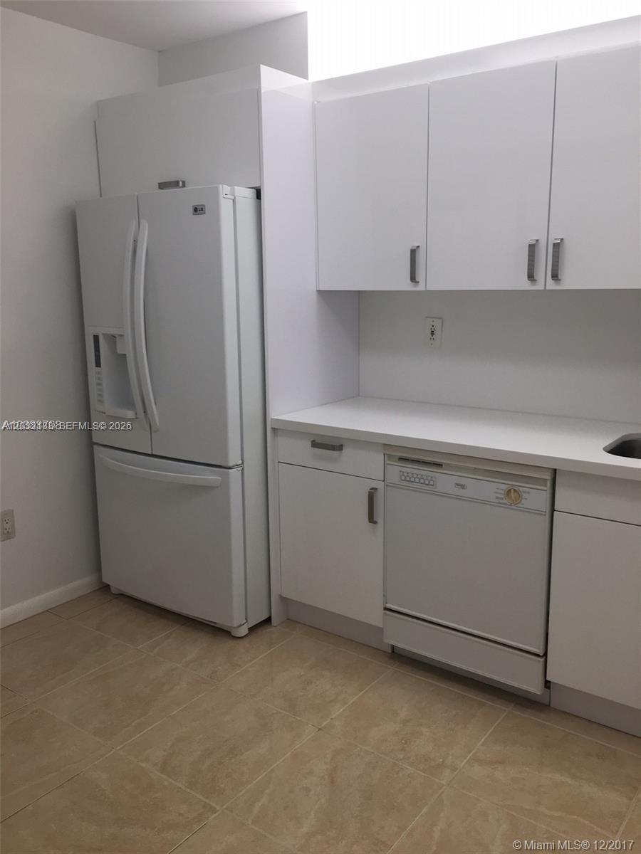 A kitchen features white cabinets, a white refrigerator, and a white dishwasher on tile flooring — 9341 Collins Ave # 1006, Surfside FL 33154, SURFSIDE, FL