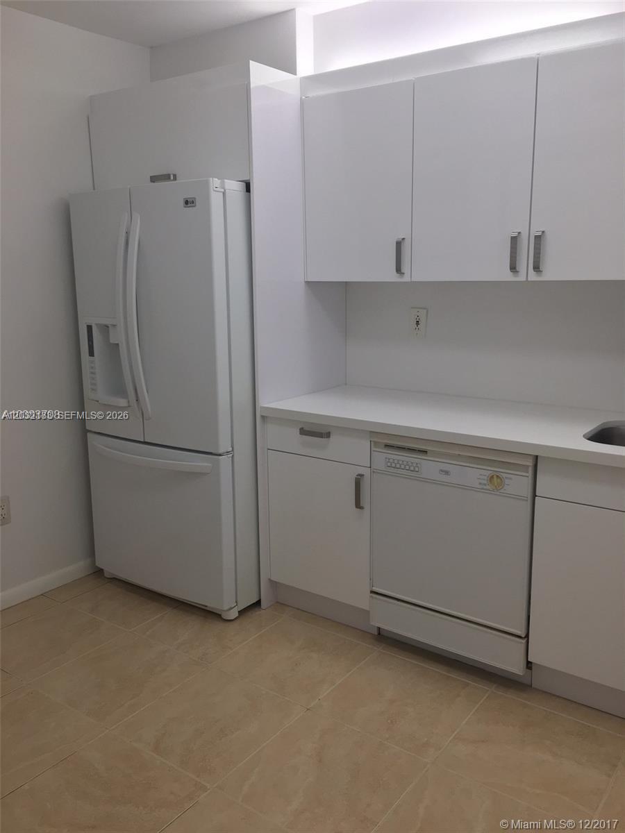 A white kitchen features a refrigerator, dishwasher, and cabinets with a light-colored countertop — 9341 Collins Ave # 1006, Surfside FL 33154, SURFSIDE, FL