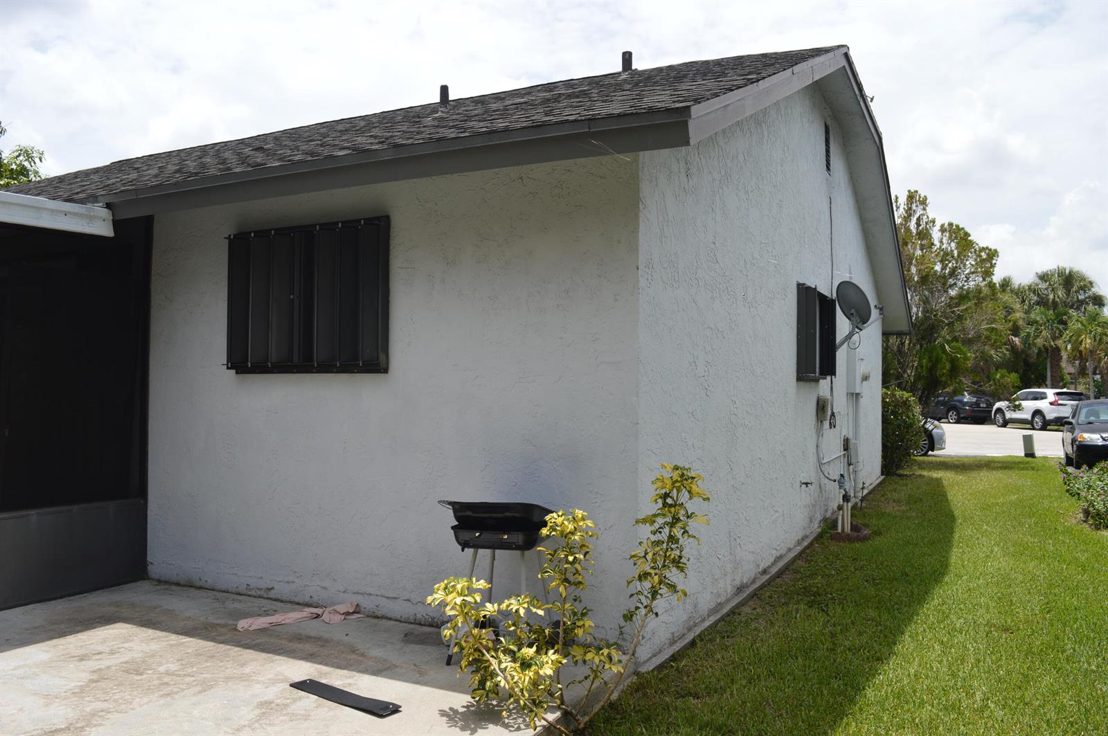 The exterior of a white stucco house features a small patio, grill, and window security bars — 9194 NW 49TH Court, Sunrise FL 33351, SUNRISE, FL