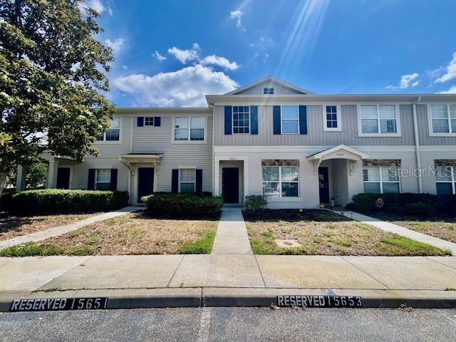 A multi-unit residential building features light-colored siding, dark shutters, and reserved parking spaces in front — 15655 STABLE RUN DRIVE, SPRING HILL, FL