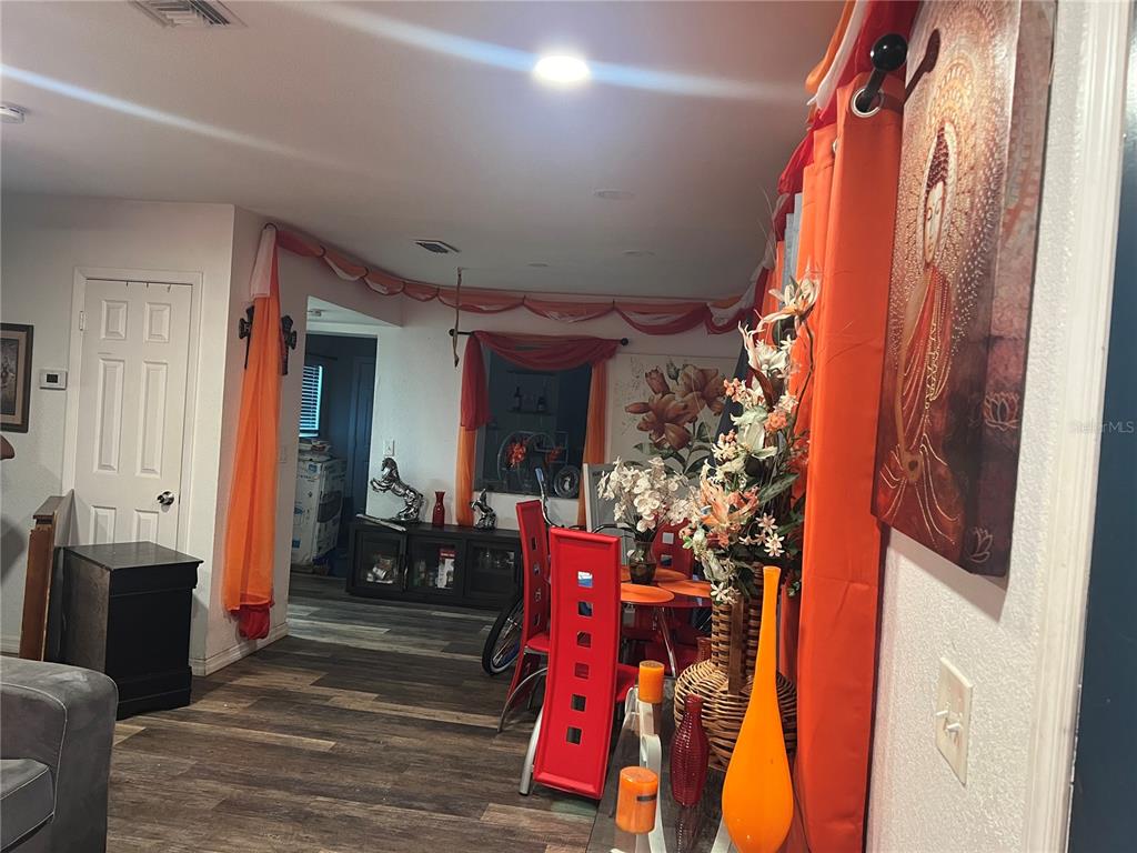 A dining area features red chairs, orange curtains, and a large Buddha wall art piece — 3945 47TH STREET, VERO BEACH, FL