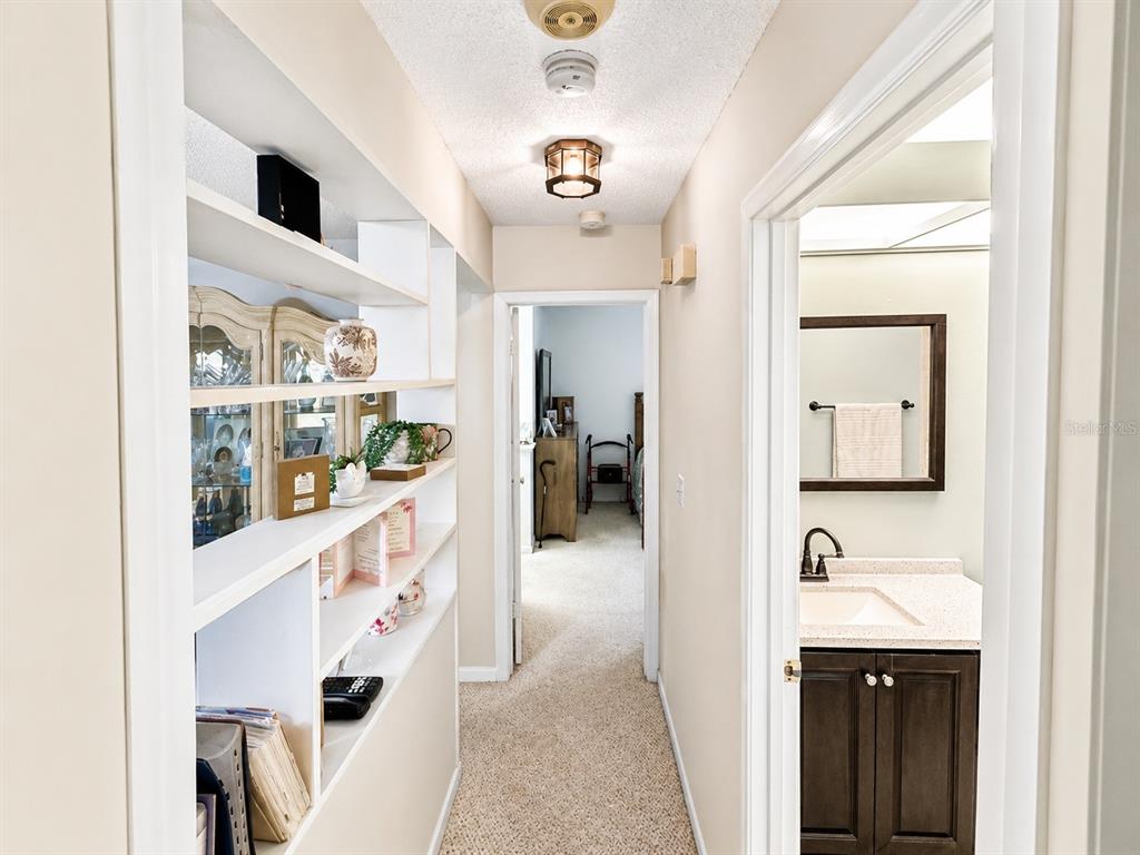 A hallway features built-in white shelving on the left and a bathroom entrance on the right — 1131 ORANGE TREE CIRCLE W UNIT C, PALM HARBOR, FL