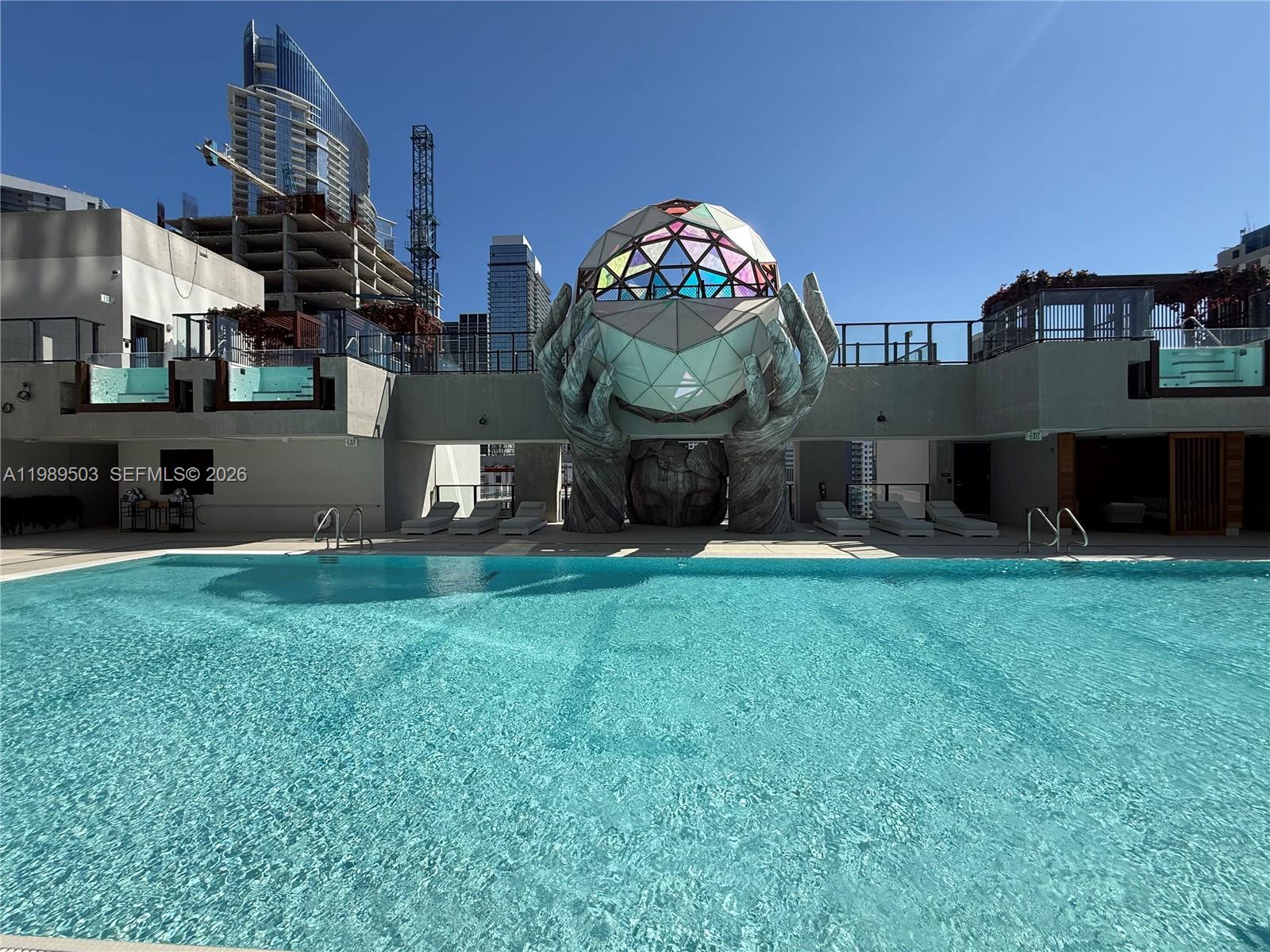 A swimming pool sits before a large sculpture of hands holding a geometric sphere — 20 NE 11th ST # 3212b, Miami FL 33132, MIAMI, FL
