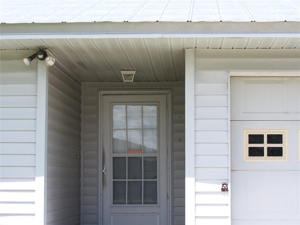 A light gray exterior features a front door with a storm door and a garage — 6061 STRICKLAND AVENUE, LAKELAND, FL