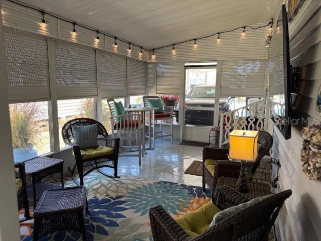 A sunroom with wicker furniture, a floral area rug, string lights, and roll-down shades — 1001 STARKEY ROAD UNIT 331, LARGO, FL