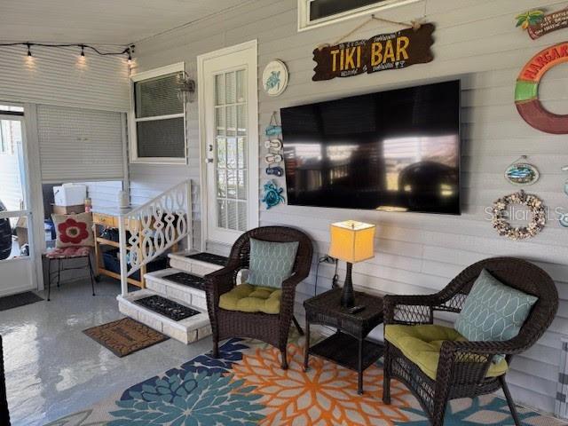 A covered porch features wicker chairs, a wall-mounted television, and a tiki bar sign — 1001 STARKEY ROAD UNIT 331, LARGO, FL