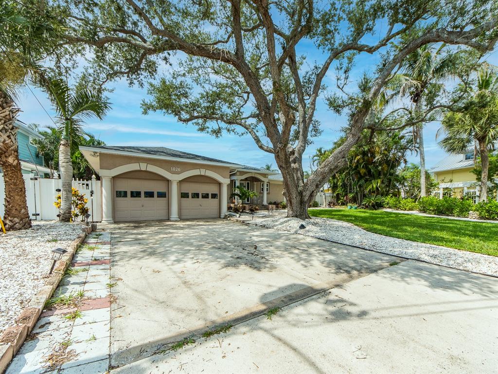 A single-story house with a two-car garage and a large tree in the front yard — 1826 VENETIAN POINT DRIVE, CLEARWATER, FL