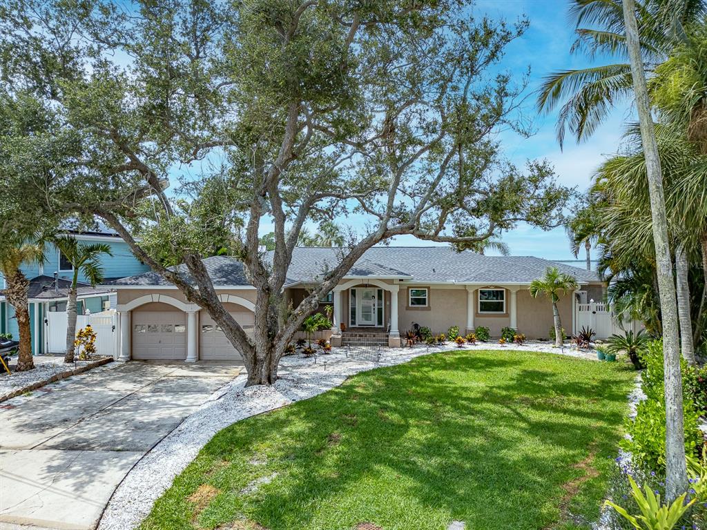 A single-story house with a two-car garage, large oak tree, and landscaped front yard — 1826 VENETIAN POINT DRIVE, CLEARWATER, FL