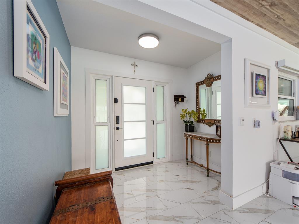 An entryway features a white front door with frosted glass panels, marble flooring, and artwork — 1826 VENETIAN POINT DRIVE, CLEARWATER, FL