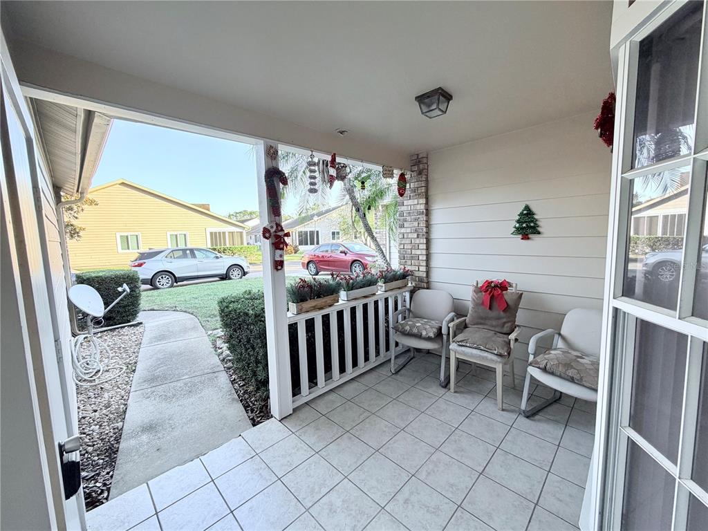 A tiled front porch features white railings, three chairs, and holiday decorations — 4523 GLEN HOLLOW, NEW PORT RICHEY, FL