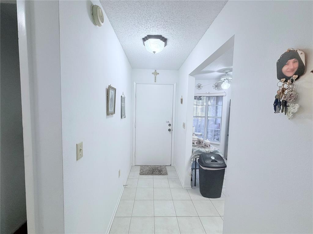 A tiled entryway leads to a white front door with a cross mounted above it — 4523 GLEN HOLLOW, NEW PORT RICHEY, FL