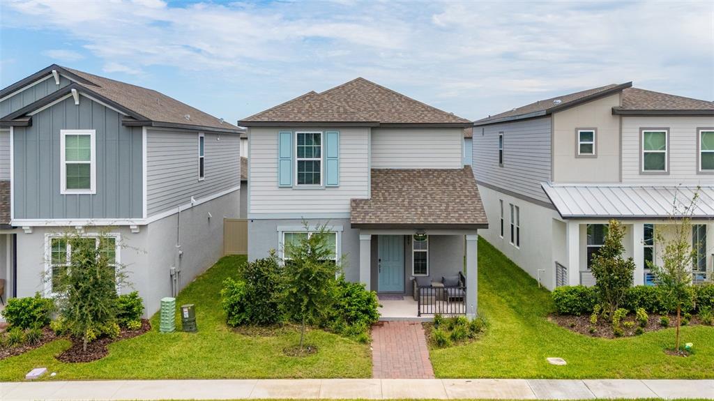 A two-story house with light gray siding, a covered front porch, and a brick walkway — 14099 FRASIER STREET, WINTER GARDEN, FL