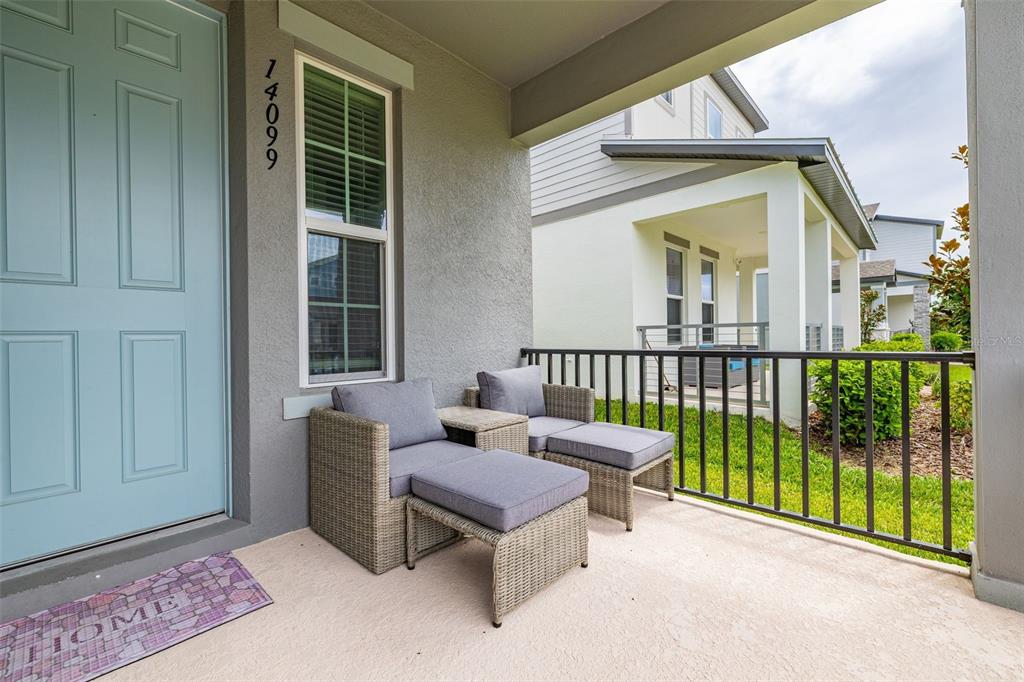 A covered front porch features two wicker chairs with ottomans and a light blue door — 14099 FRASIER STREET, WINTER GARDEN, FL