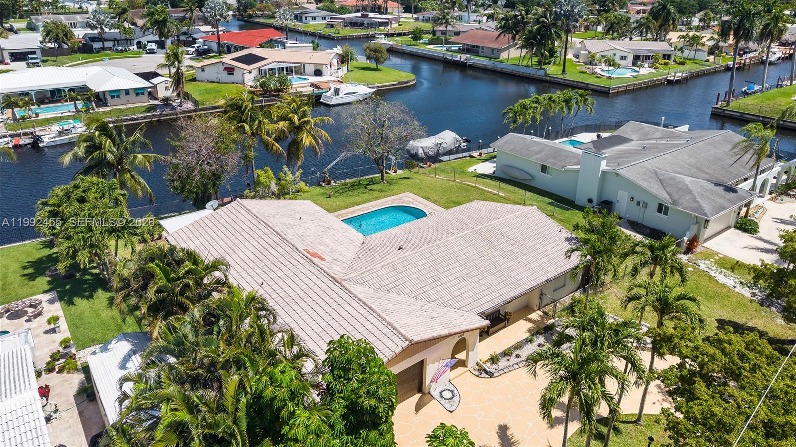 An aerial view shows a house with a tiled roof, pool, and canal access — 6121 SW 16th St, Plantation FL 33317, PLANTATION, FL