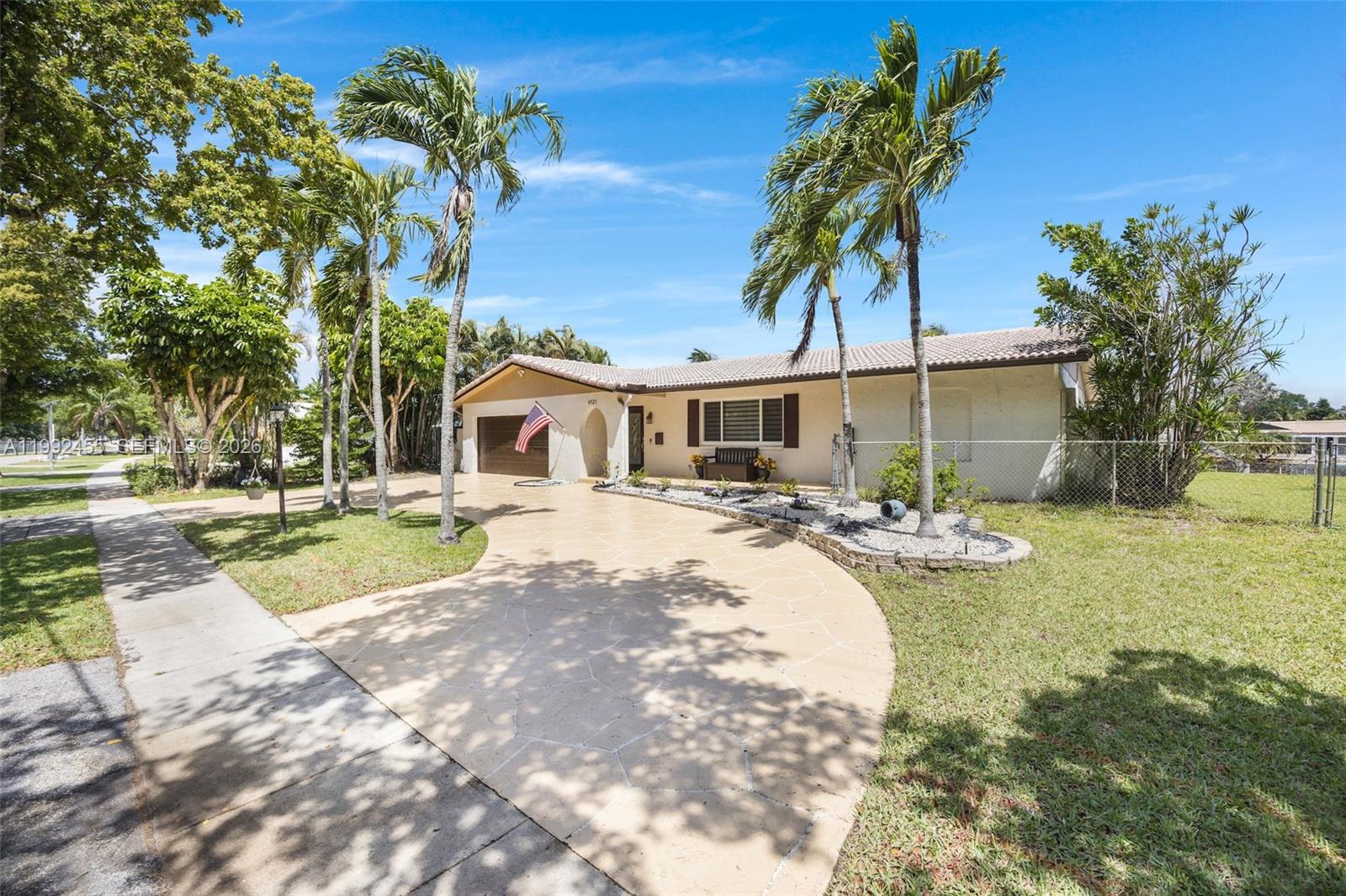 A single-story house with a paved driveway, palm trees, and a chain-link fence — 6121 SW 16th St, Plantation FL 33317, PLANTATION, FL