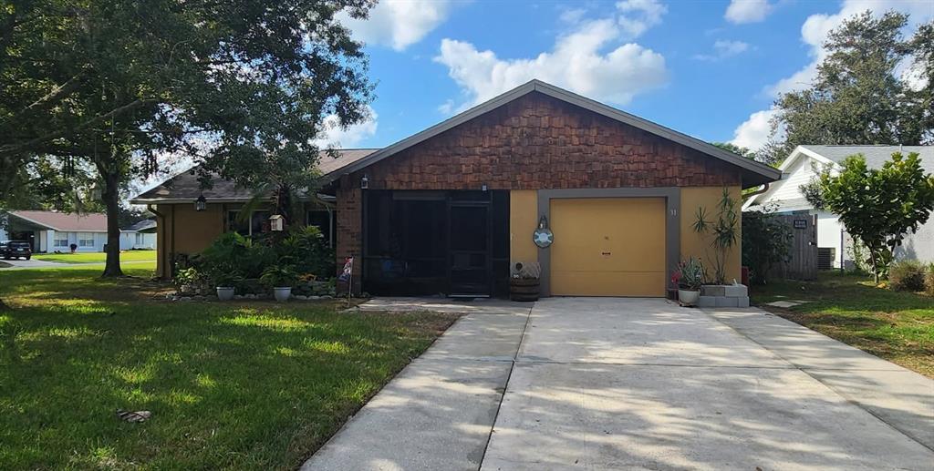 A single-story house features a tan garage, a screened-in entryway, and wood-shingled gable siding — 31 CHIP COURT, KISSIMMEE, FL