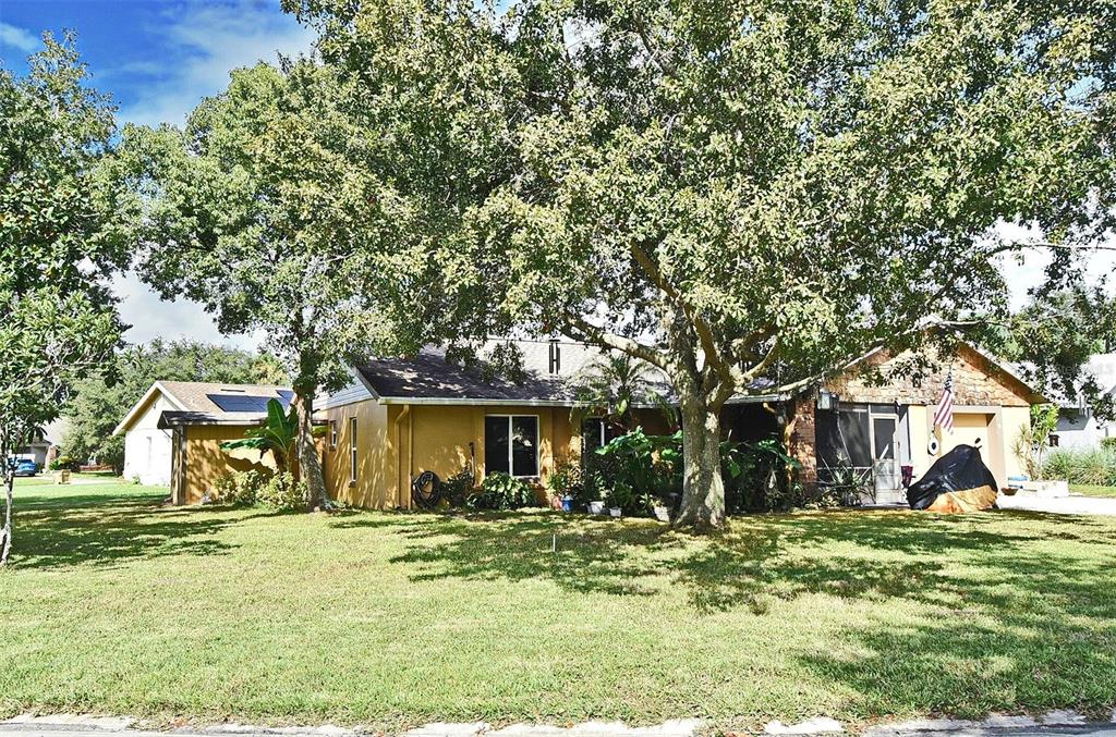 A single-story house with a yellow exterior, a screened porch, and large shade trees — 31 CHIP COURT, KISSIMMEE, FL