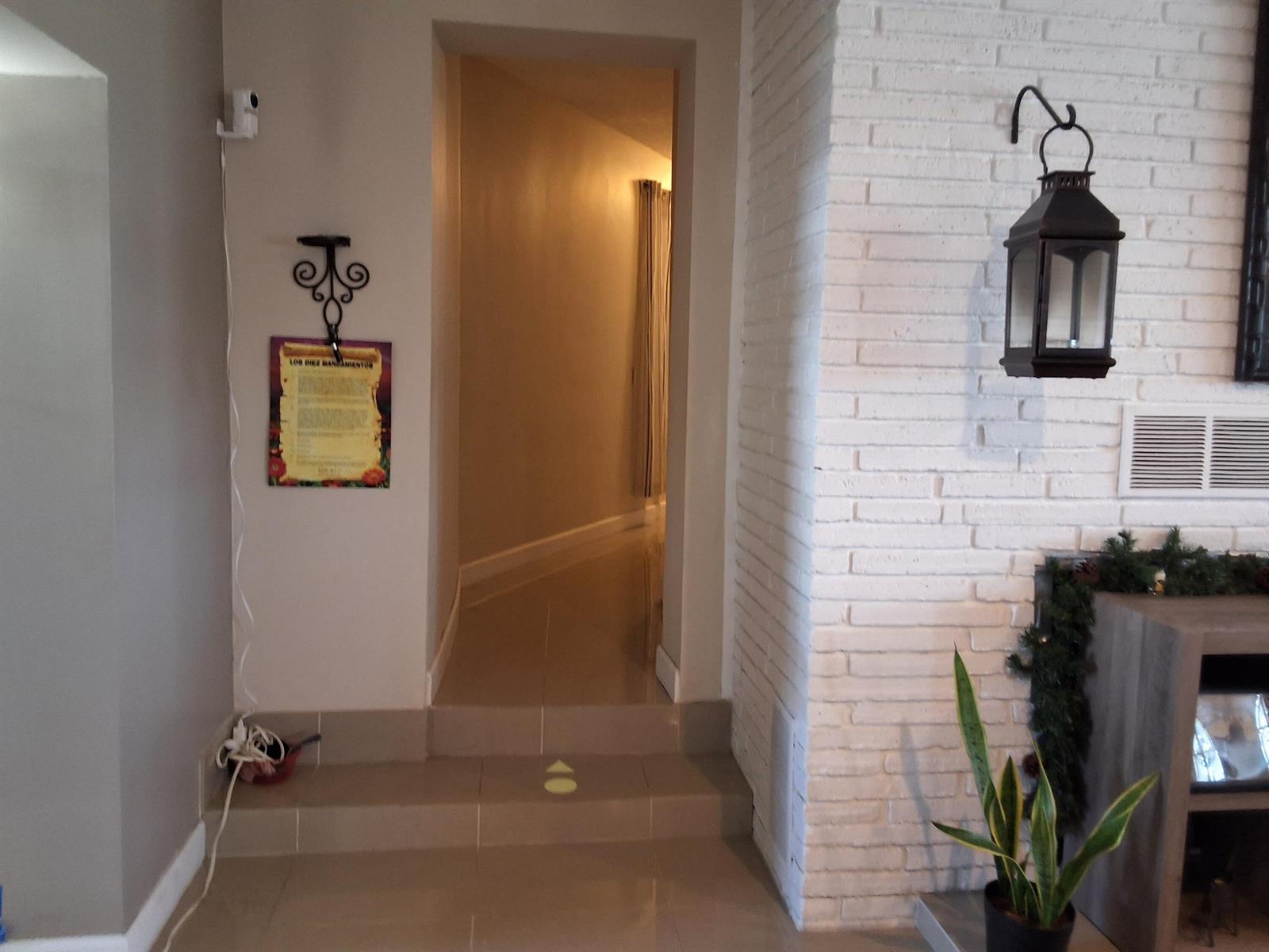 A tiled hallway leads through a doorway next to a white brick fireplace wall — 1221 Bacom Point Road, Pahokee FL 33476, PAHOKEE, FL
