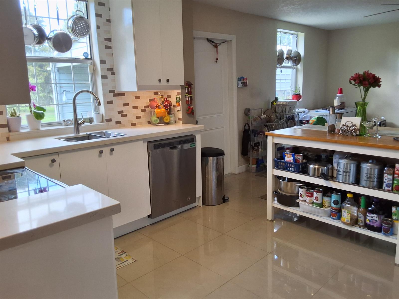 A kitchen features white cabinetry, stainless steel appliances, a tiled backsplash, and an open island — 1221 Bacom Point Road, Pahokee FL 33476, PAHOKEE, FL