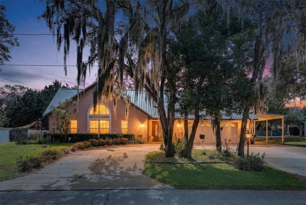 A single-story house with a metal roof and a concrete driveway at twilight — 2725 W CHARING ROAD, AVON PARK, FL