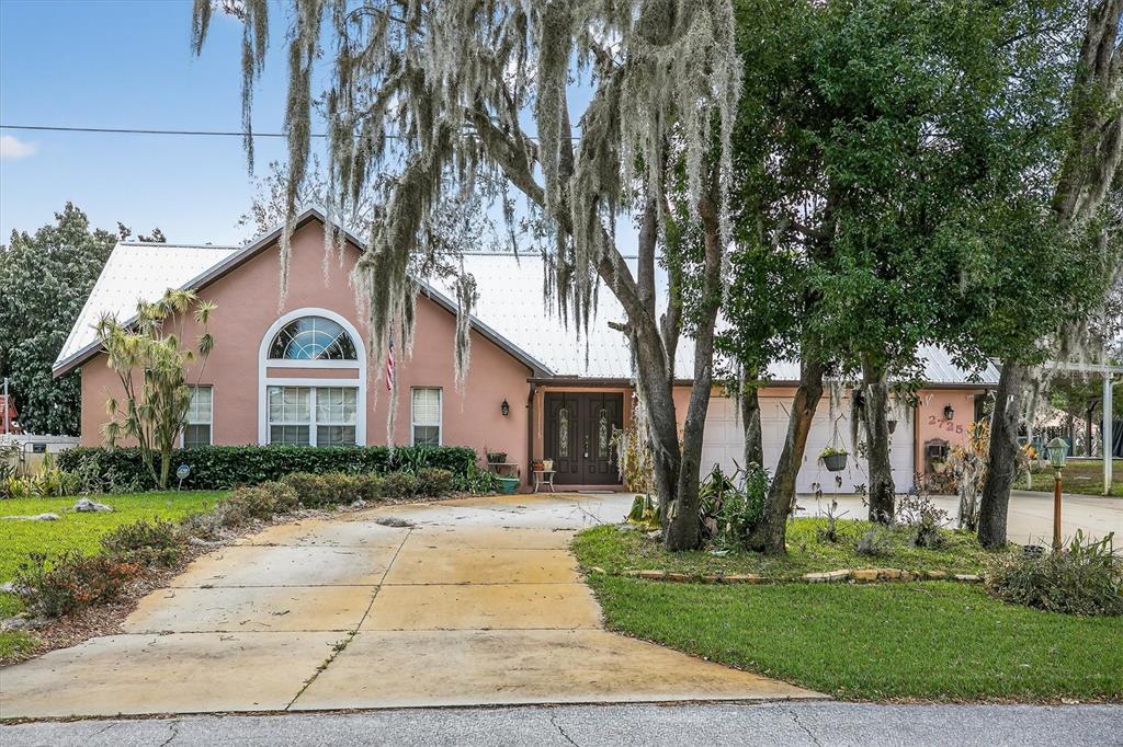 A single-story house with a metal roof, stucco exterior, and a concrete driveway — 2725 W CHARING ROAD, AVON PARK, FL