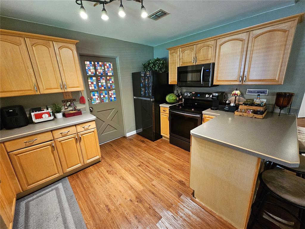 A kitchen features light wood cabinets, gray countertops, black appliances, and a stained-glass door — 1908 WEEKS AVENUE, ORLANDO, FL
