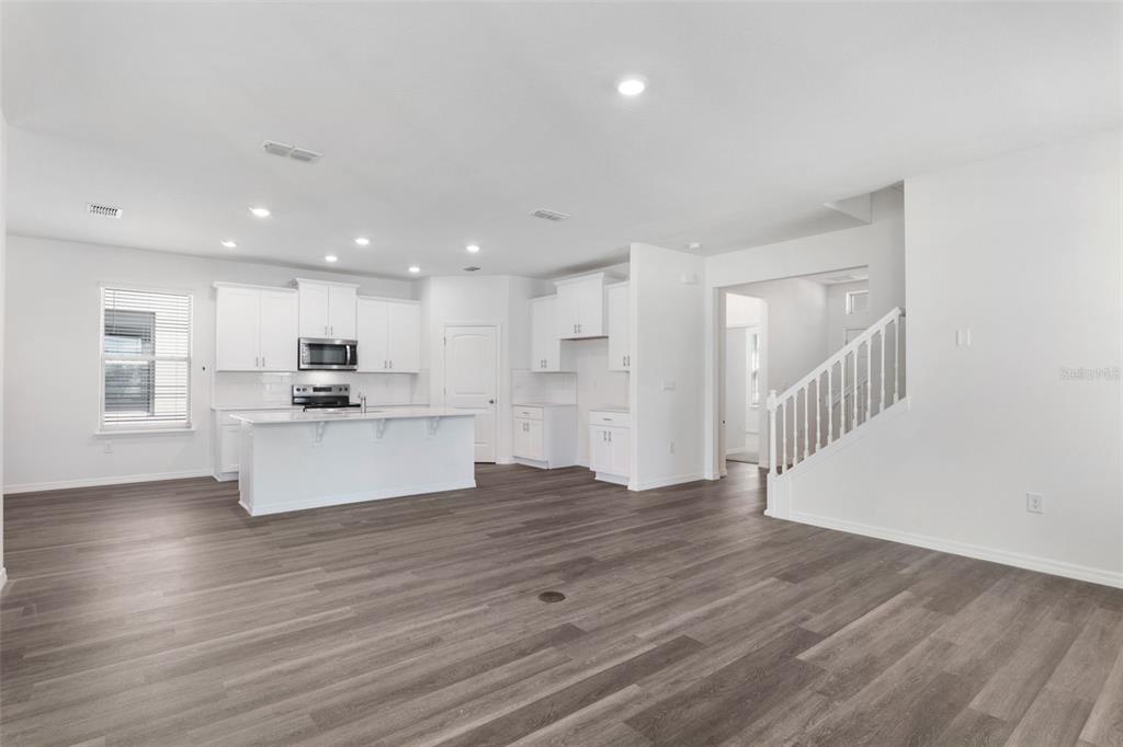 A bright, open-concept kitchen features white cabinetry, a central island, and wood-look flooring — 16822 HOBE SOUND COURT, WINTER GARDEN, FL
