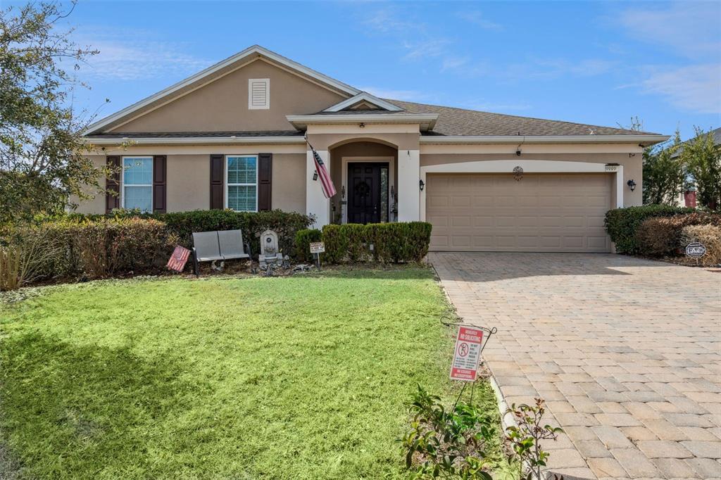 A single-story house with a beige stucco exterior, a two-car garage, and a paved driveway — 9889 LENOX STREET, CLERMONT, FL