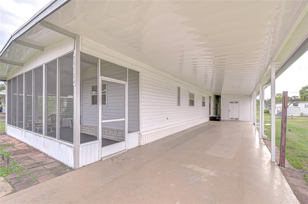 A mobile home exterior featuring a screened-in porch and a long covered carport — 39524 DUNDEE ROAD, ZEPHYRHILLS, FL