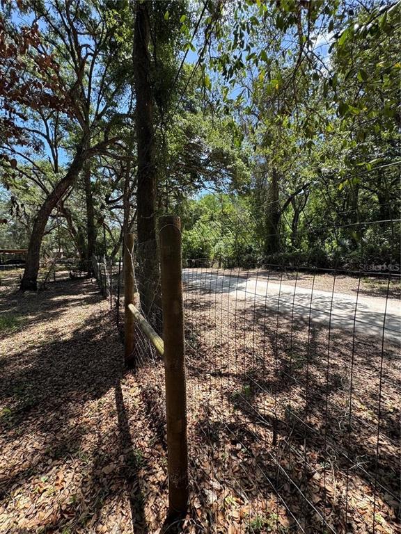 A wire fence with wooden posts runs along a dirt road through a wooded area — TANNAHILL STREET, DADE CITY, FL