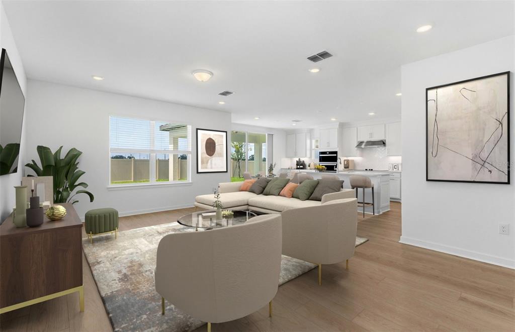This open-concept living room features a sectional sofa, two armchairs, and an adjacent kitchen — 7910 PALM PARADISE PLACE, PARRISH, FL