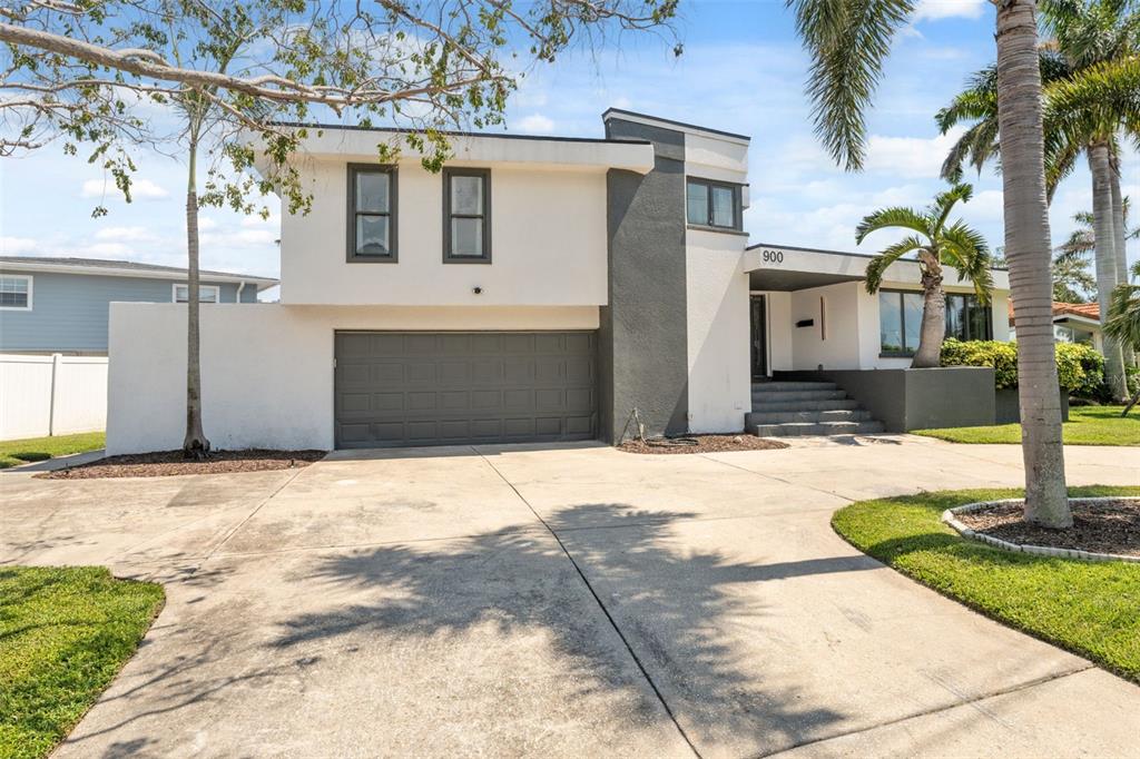 A two-story house with a white and gray exterior, a garage, and a palm tree — 900 79TH STREET S, ST PETERSBURG, FL