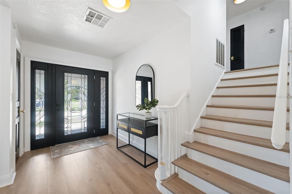An entryway features a black front door, a console table, and stairs with wood treads — 900 79TH STREET S, ST PETERSBURG, FL