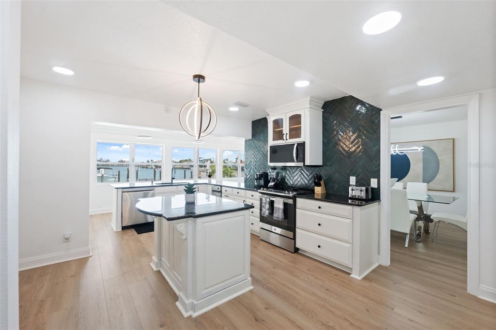 A kitchen features white cabinets, a dark herringbone backsplash, a center island, and water views — 900 79TH STREET S, ST PETERSBURG, FL