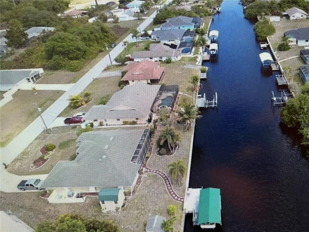 An aerial view shows several waterfront houses along a canal with private boat docks — 12338 KNEELAND TERRACE, PORT CHARLOTTE, FL
