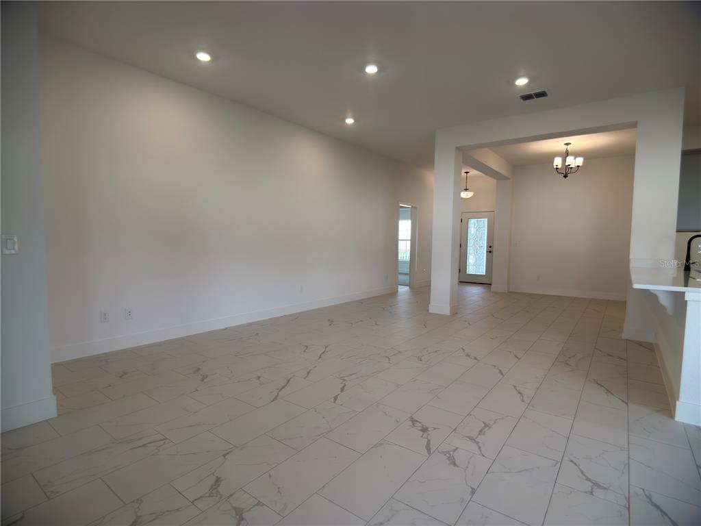 An open-concept kitchen and living area features gray cabinets, white countertops, and marble-look tile flooring — 3147 NE 45TH AVENUE, OCALA, FL