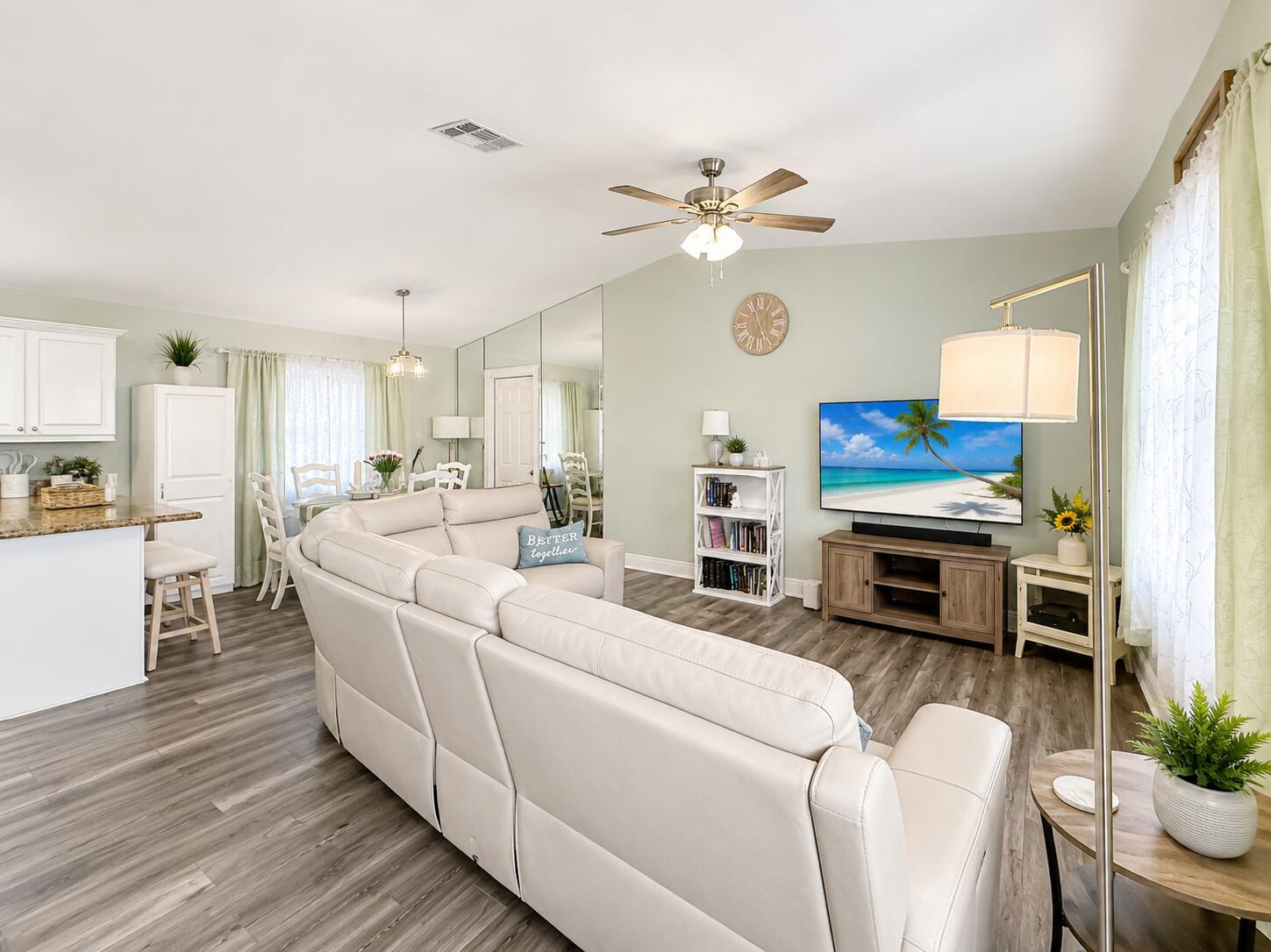 A living room features a white sectional sofa, a television, and light green walls — 4436 SE Beckett Avenue, Stuart FL 34997, STUART, FL