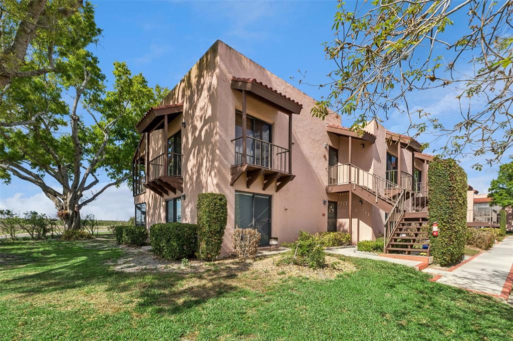 A two-story stucco apartment building with exterior staircases and balconies under a clear blue sky — 210 LA CASA UNIT 210, LAKE WALES, FL