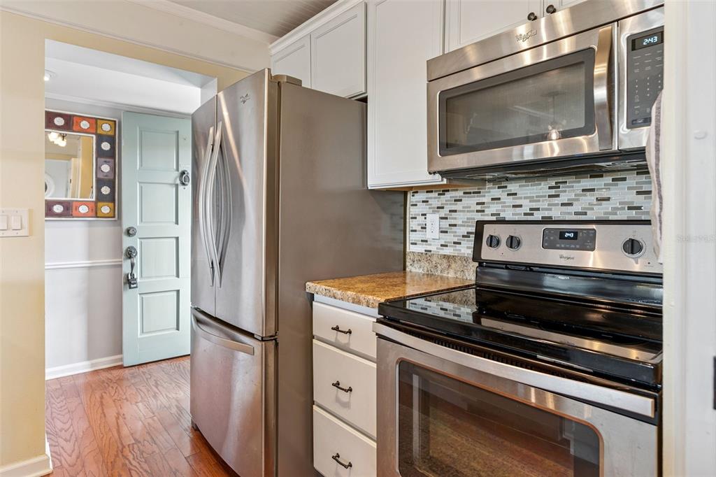 A kitchen features stainless steel appliances, white cabinets, granite countertops, and a light blue door — 210 LA CASA UNIT 210, LAKE WALES, FL